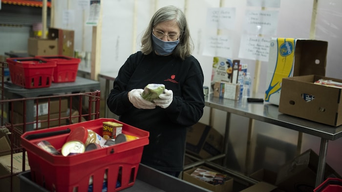 Una voluntaria coloca alimentos en una canasta en un banco de alimentos en Ottawa.