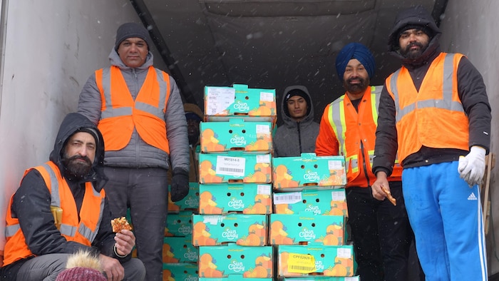 Des bénévoles avec des caisses d'oranges.