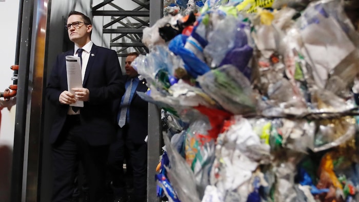 Le ministre de l'Environnement, Benoit Charette et des matières recyclables dans un centre de tri.