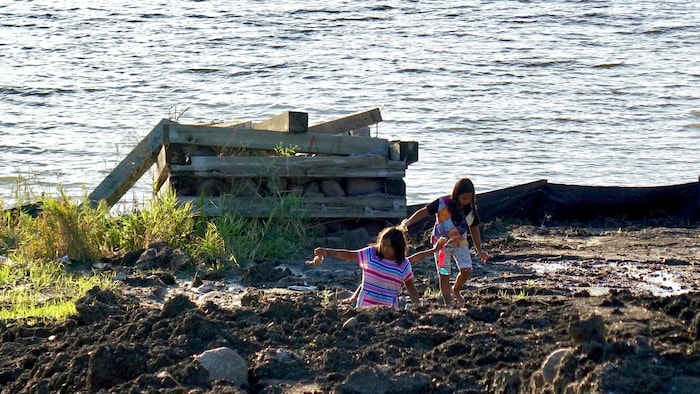 Deux jeunes Autochtones marchent sur un terrain près d'un cours d'eau. 
