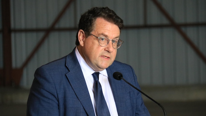 Le ministre parle à une foule derrière le micro d'un lutrin.
