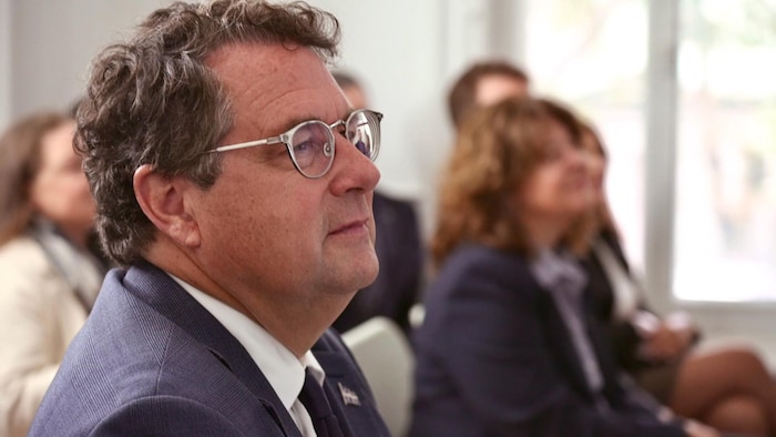 Un homme est assis dans une salle et écoute attentivement.
