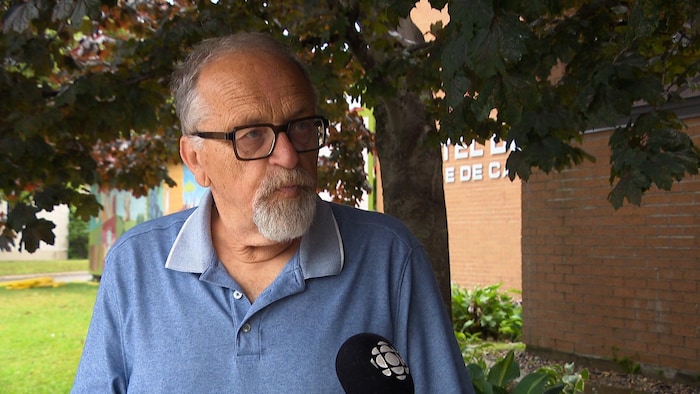 Un homme interviewé devant l'hôtel de ville.