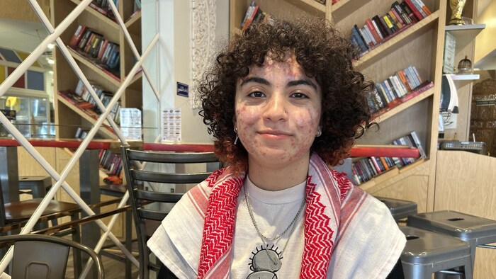 Une femme souriante est assise avec un keffieh autour du cou.