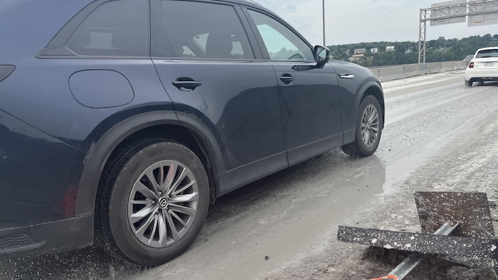Une voiture roule dans du béton sur un pont.
