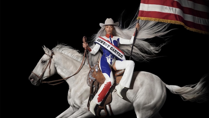 La chanteuse est assise à l'envers sur un cheval avec un drapeau américain. 