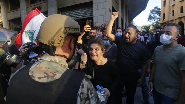 Un soldat libanais fait face à une femme en colère et à des dizaines de manifestants derrière elle.