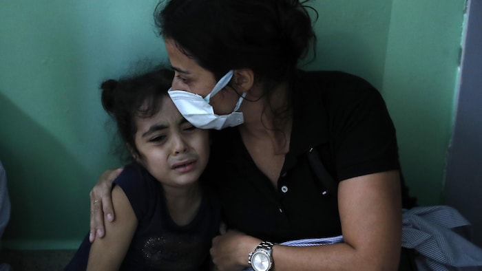 Une femme serre une enfant qui pleure dans ses bras.