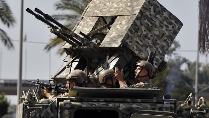 Des soldats dans un char pointent leurs armes.