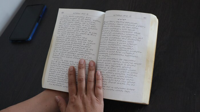 Une main tient une bible en inuktitut.