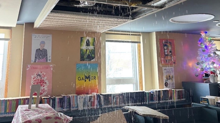 Un dégât d'eau dans une bibliothèque. De l'eau s'échappe d'un énorme trou au plafond.