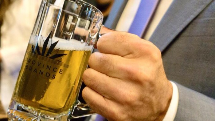 Une main tient un bock de bière de marque Province Brands of Canada.