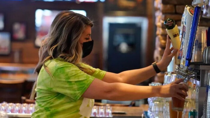 Une serveuse sert une bière dans un bar.