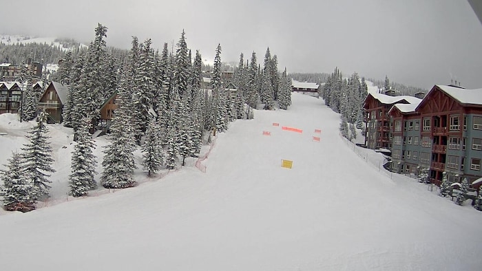 Une piste de ski enneigée bordée de chalets.