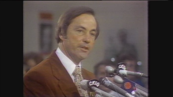 Bill Bennett parle devant des microphones en conférence de presse.