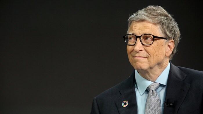 Bill Gates portant un veston, pris en photo sur un fond sombre.