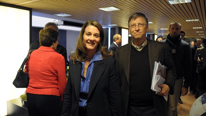 Bill et Melinda Gates marchent dans une foule dans un centre de congrès.