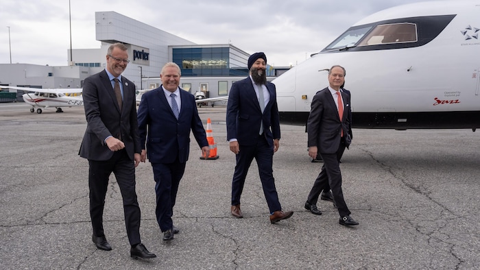 Le président et chef de la direction de l’Administration portuaire de Toronto, RJ Steenstra (de gauche à droite), le premier ministre de l’Ontario, Doug Ford, Prabmeet Singh Sarkaria et le ministre des Finances de l’Ontario, Peter Bethlenfalvy, arrivent à un événement à l’aéroport Billy Bishop de Toronto le lundi 23 mars 2026.