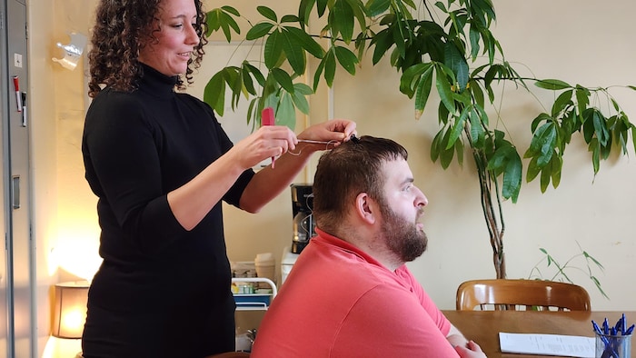 Une femme prend un échantillon de cheveu à un patient. 