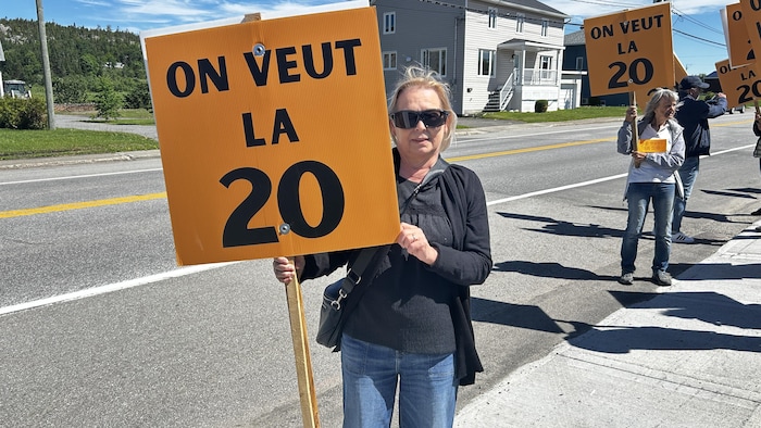 Une femme tient une pancarte lors d'une manifestation.