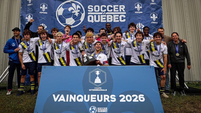 Des jeunes joueurs de soccer, médailles au cou, posent en vainqueurs en compagnie de leurs entraîneurs.