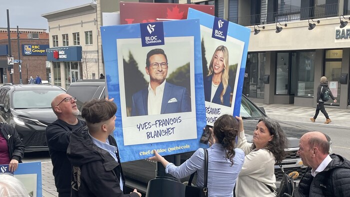 Des militants tiennent des pancartes.