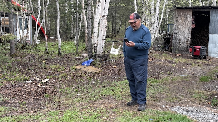 Un homme regarde son téléphone en forêt.
