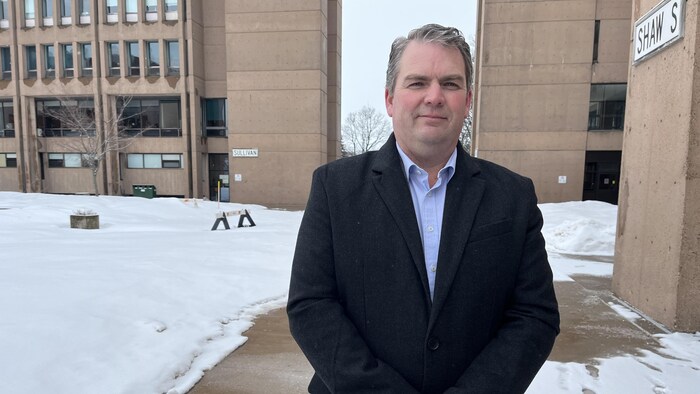 Un homme devant un édifice à l'extérieur, en hiver.