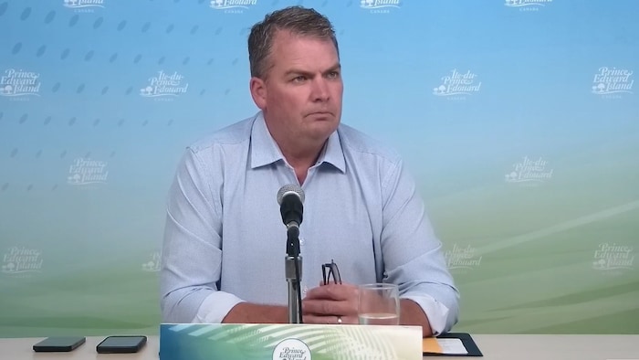 Le ministre écoute une question posée par un journaliste lors de la conférence de presse.