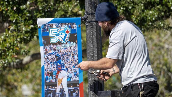 Un homme pose une affiche de Vladimir Guerrero fils sur un poteau.