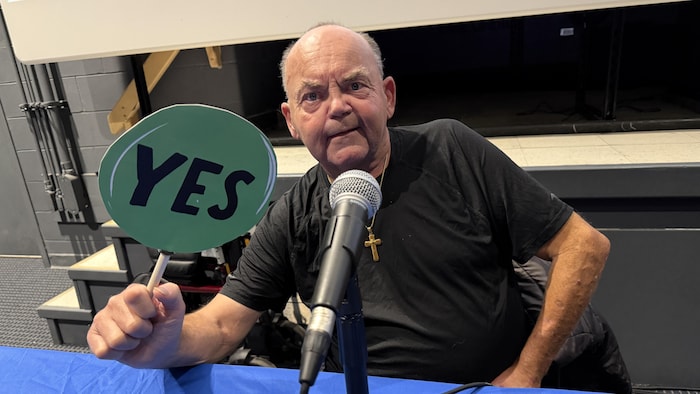 Un homme avec une pancarte, devant un microphone.