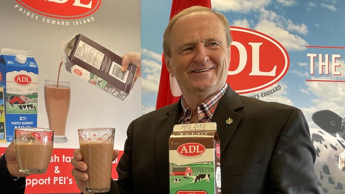 Bobby Morrissey regarde vers la droite. Il lève un verre de lait au chocolat d'une main et tient une pinte de lait au chocolat de l'autre.
