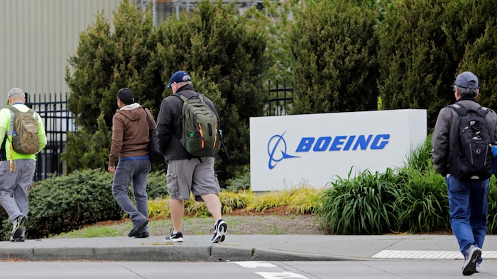 Des personnes de dos se dirigent vers l’entrée d’une usine de Boeing.