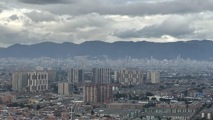 Un paysage urbain avec en arrière-plan les montagnes. Un smog plane sur la ville. 