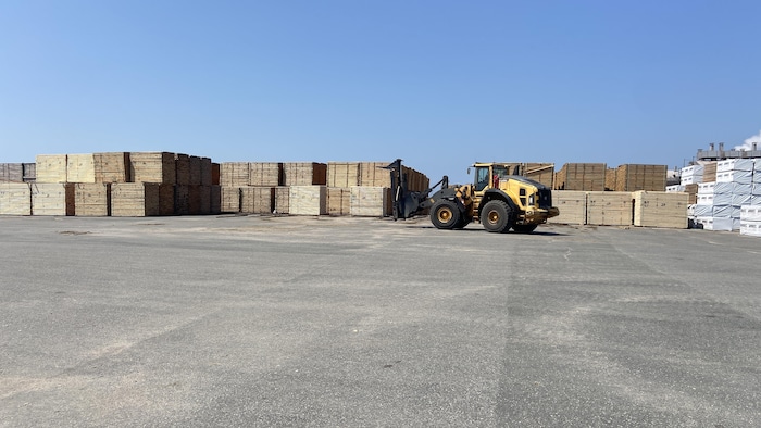 Un camion élévateur circule entre des piles de bois d'œuvre.