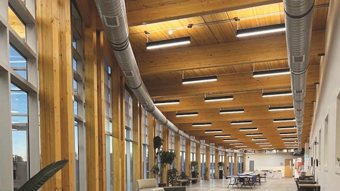 Vue de l'intérieur de l'édifice avec un plafond en bois et des poutres portantes en bois.