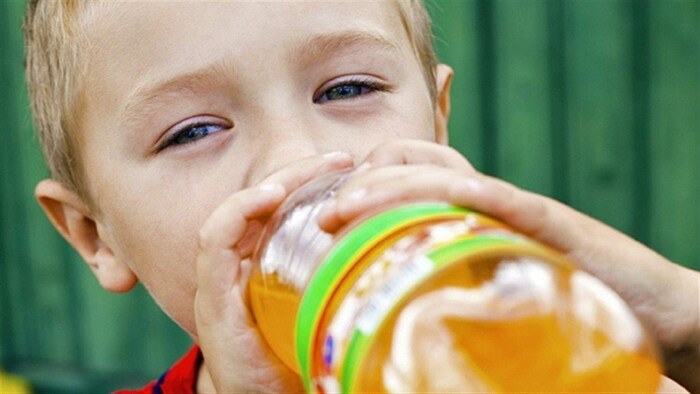 Un enfant boit une boisson gazeuse.