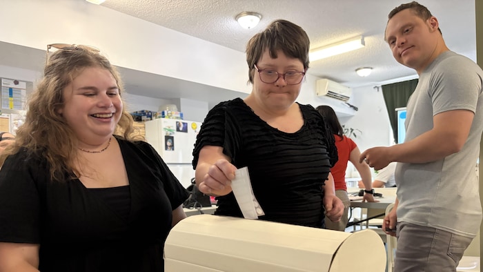 Une personne insère un bulletin de vote dans une boîte de scrutin.