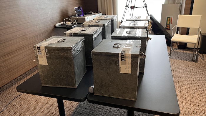 Des boîtes scellées remplies de votes sont déposées sur une table.