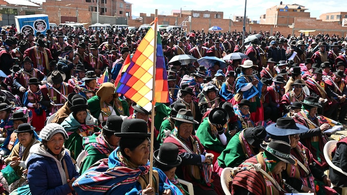 Une femme brandit un drapeau wiphala lors d'une réunion des dirigeants des « Ponchos Rojos » visant à discuter de l'avenir des manifestations qui se poursuivent depuis plus de six semaines à Tilata, dans le département de La Paz, en Bolivie, le 18 juin 2026.

