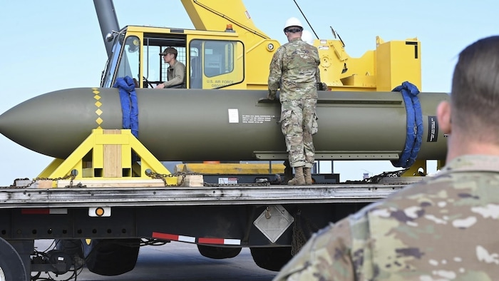 Trois soldats observent une bombe sur un camion. 