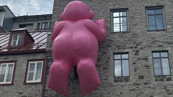 Un gros bonhomme nu est accroché à un bâtiment.