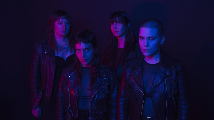 Un groupe de personnes dans une ambiance sombre et qui regardent vers l'objectif de la caméra.