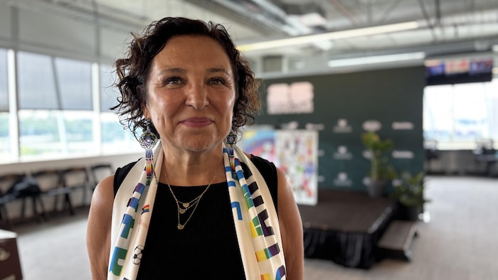 Une femme regarde la caméra avec une écharpe multicolore sur le cou. 