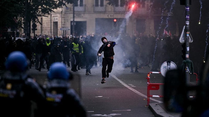 Un manifestant lance une fusée fumigène en direction des gendarmes français.