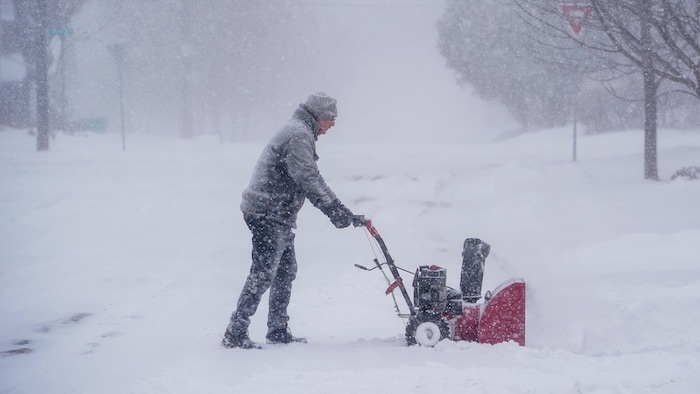 Une personne pousse une souffleuse.