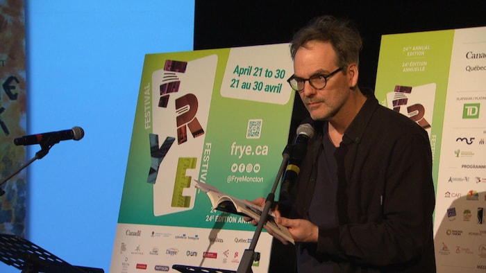 Paul Bossé lit un passage d'un livre devant le public.