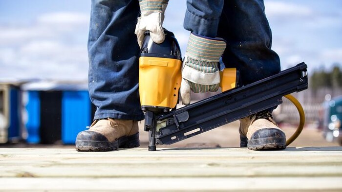 Une personne cloue avec des bottes et des gants de sécurité.