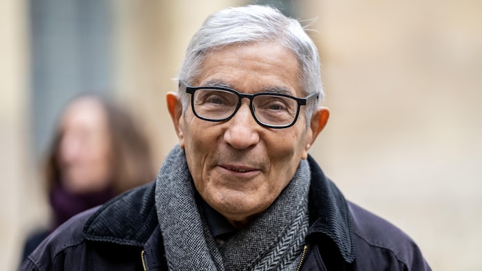 Un homme aux cheveux blancs porte des lunettes. 