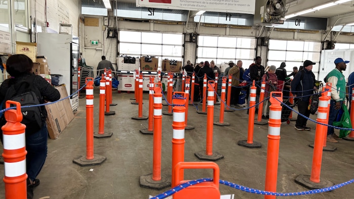 Une file d'attente de quelques dizaines de personnes dans un grand garage.